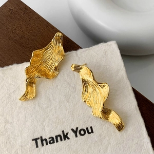 Boucles d'oreilles dorées irrégulières avec texture plissée sur papier cartonné