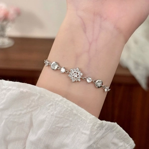Elegantes Silberarmband mit Zirkonia-Schneeflocke am Handgelenk einer Frau getragen