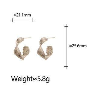 Detail of twisted gold C-shaped earrings with textured surface and size dimensions