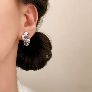 Polished silver irregular pleated wave earrings on female model for a minimalist look