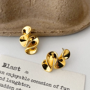 Detailed close-up of golden twisted swirl stud earrings with a polished metallic finish
