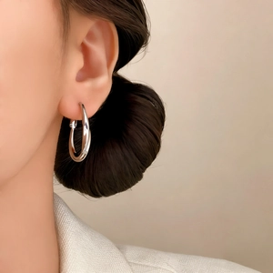 Elegant geometric oval hoop earrings in polished silver finish on female model