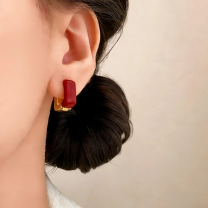 Elegant rectangular red enamel stud earrings with gold metal base on model