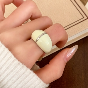 Retro cream white enamel ring with silver metal band on vintage book background