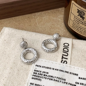 Minimalist silver geometric hammered metal hoop earrings set on a rustic vintage background