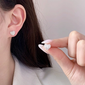 Elegant silver heart stud earrings with micro-pave crystals on a female model