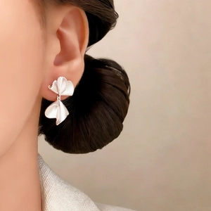 Elegant matte silver bowknot earrings in petal design worn by a female model