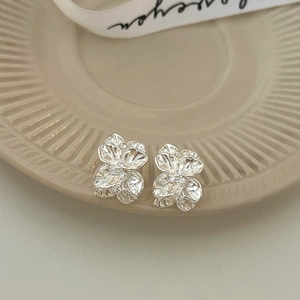 Detail of silver pleated flower stud earrings featuring shimmering crystal center accents