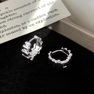 Macro shot of silver metal hoop earrings with textured finish on black velvet tray