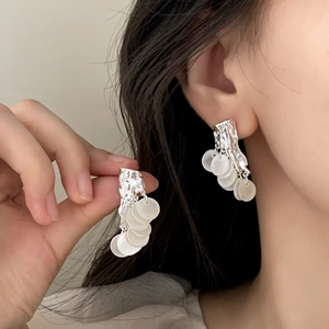 Silver fringe earrings with irregular metal plates and white shell charms on model