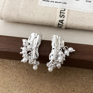 Detail of silver irregular textured earrings with elegant hanging white pearl clusters