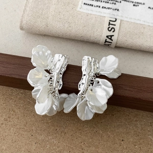 Detail shot of silver metal petal earrings with elegant white shell-like floral elements