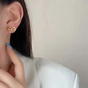 Elegant gold bow earrings with a minimalist knotted design shown on a female model