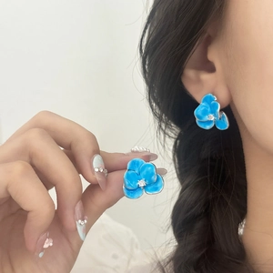 Elegant silver flower stud earrings with blue enamel petals and zircon center on model