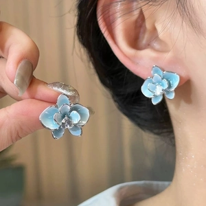 Elegant gradient blue flower stud earrings with a sparkling zircon center on model