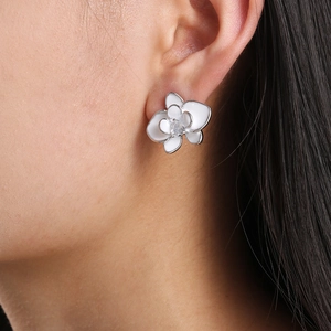 Elegant white enamel orchid stud earrings with zircon center worn by model