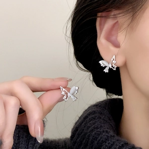 Elegant silver butterfly stud earrings with white opal wings and zircon accents on model