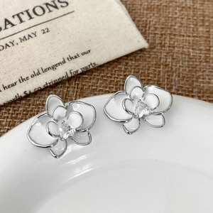 Macro shot of orchid flower earrings with white enamel and heart-shaped crystal on ceramic