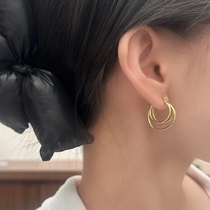 Elegant gold-tone triple hoop earrings for women shown on model for a luxury metal aesthetic