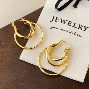 Detail of layered triple-hoop gold earrings with polished 18K finish on a display surface