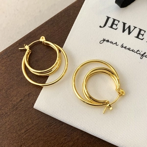Detailed close-up of gold multi-layered hoop earrings with polished geometric circles
