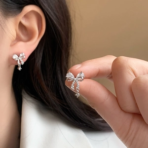 Sparkling silver bow knot earrings with micro-set zircon stones shown on ear model