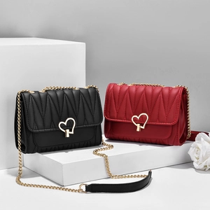 Quilted crossbody saddle bags with gold heart locks and chain straps on geometric stands