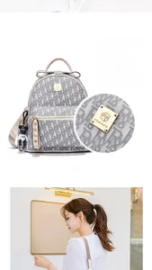 Close-up of golden metal logo plate and panda charm on grey monogram backpack