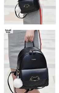 Detail of small black quilted backpack with cat metal buckle and white fur ball charm