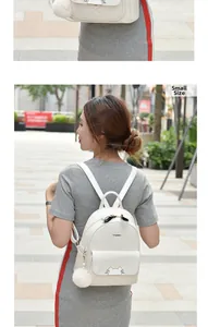 Outdoor shot of a small white quilted PU backpack with cute cat ears and a fur pompom