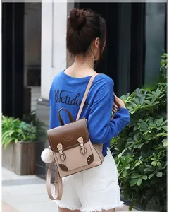 Detail of stylish brown and beige faux leather backpack with plush ball and bear motif