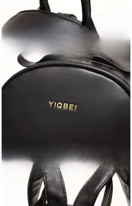 Detail view of black lychee-textured leather backpack with golden YIQBEI letter embossing
