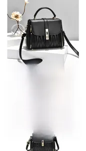 Detail of black leather handbag with V-shaped quilting and elegant gold metal hardware