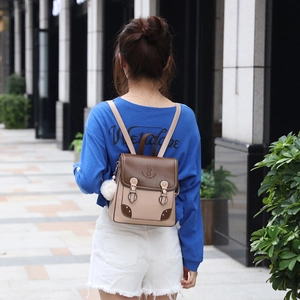 Two-tone mini backpack with bear logo and plush charm shown in an outdoor lifestyle shot