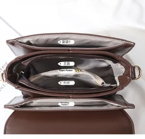 Vertical view of deep brown faux leather crossbody bag with multiple internal compartments