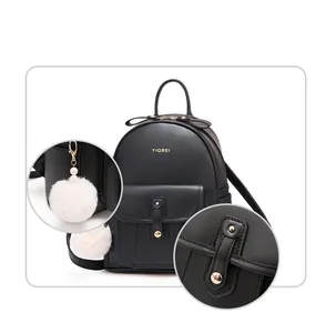Détail d'un sac à dos en cuir noir avec boucle dorée, logo et pompon à perles