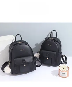 Détail d'un sac à dos en cuir noir souple avec nœud et breloque boule de poils à perle