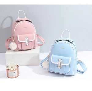 Détail de mini sacs à dos en cuir rose et bleu avec pompon décoratif et logo doré