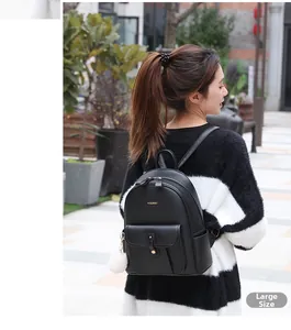 Détail d'un grand sac à dos en cuir noir souple avec logo doré et pompon blanc décoratif