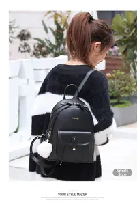 Détail d'un petit sac à dos en cuir noir avec pompon blanc et finitions dorées