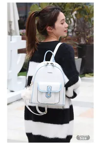 Photo de petit sac à dos en cuir PU blanc avec bordure bleue et pompon blanc en plein air