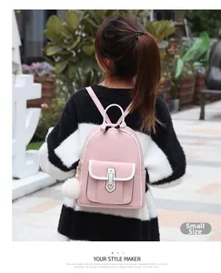 Détail du petit sac à dos en cuir rose et blanc avec pompon peluche sur un modèle femme