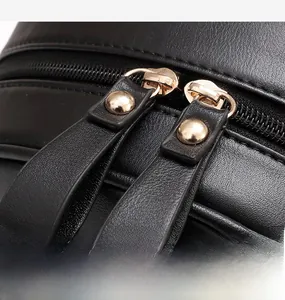 Détail des fermetures éclair doubles en métal doré avec tirette en cuir noir sur le sac à dos