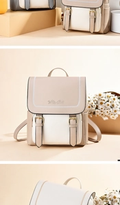 Detail view of floral embroidery and gold buckle straps on a beige leather backpack