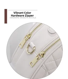 Detail of gold metal zipper and D-ring on white quilted leather crossbody bag