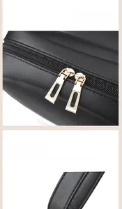 Detailed view of dual golden zippers and reinforced D-rings on a black leather backpack