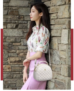 Close-up of white quilted crossbody bag with gold floral logo and leather texture