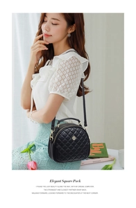 Close-up of black quilted round crossbody bag featuring golden clover metal logo
