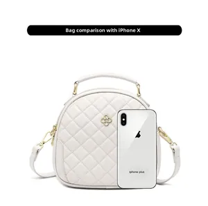 Compact white quilted round crossbody bag shown next to a smartphone for size scale