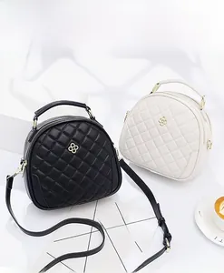 Detail of black and white quilted round crossbody bags with gold clover metal hardware